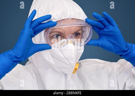 Selbstbewusster und ernsthafter Arzt in Schutzanzug und Maske mit Brille Stockfoto