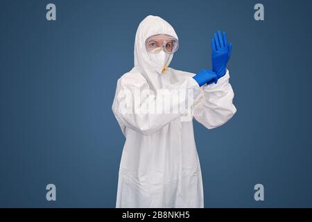 Selbstbewusster Arzt in Schutzkleidung und Gesichtsmaske tragen Handschuhe Stockfoto