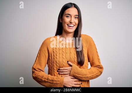 Junge schöne Brunette-Frau mit legeren Pullover über isoliertem weißem Hintergrund lächelnd und lachend laut, weil lustig verrückt Witz mit Stockfoto