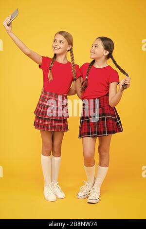 Lustige Freunde. Spaß. Schwesternschaft und Freundschaft. Glücklich wissen Tag. Kindheit Glück. Bildung Konzept. zurück zu Schule. sozialen Netzwerk. Mädchen in Uniform. kleine Mädchen selfie am Telefon. Stockfoto