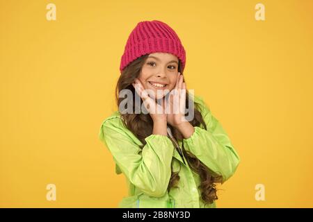 Zwischen den schönsten und trendigsten Wählen. Junge Mädchen tragen Strickmütze. Winter hat Zubehör. Mädchen lange Haare gelb hinterlegt. Kalten Jahreszeit Konzept. Winter Fashion Accessoire. Kleines Kind tragen warme Mütze. Stockfoto