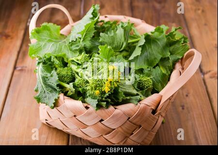 Rohbio Turnip Greens auf braunem Holzhintergrund . Korb mit frischem grünen Gemüse . Italienische Küche. Oben Stockfoto