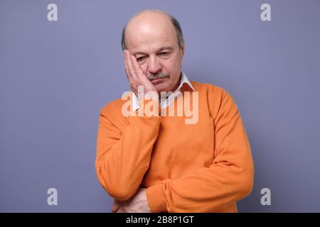 Traurig reifen hispanischen Mann in orange Pullover Gefühl gestresst und allein. Stockfoto