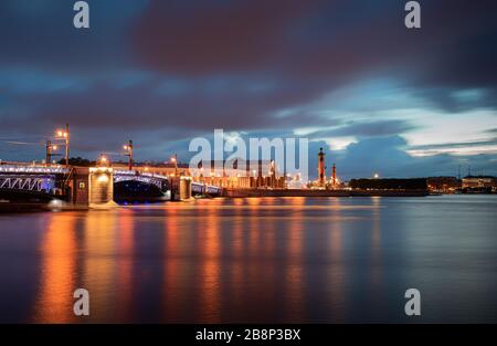 Schöne weiße Nachtansicht auf der beleuchteten Palacebrücke, Neva Böschung und Rastersäulen. Alle sind berühmte Wahrzeichen der Stadt Sankt Petersburg, R. Stockfoto