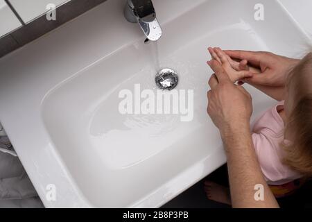 Vater hilft seinem Kind, die Hände mit Seife zu waschen, um Corona-Viren zu verhindern Stockfoto