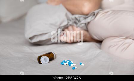 Schließen Sie die invertierte offene Arzneiflasche auf dem Bett. Stockfoto