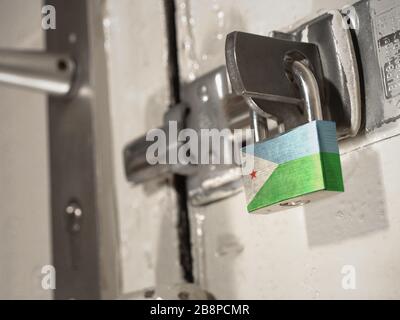Eine verschraubte Tür, die mit einem Vorhängeschloss mit der Nationalflaggen Dschibutis darauf gesichert ist.(Serie) Stockfoto
