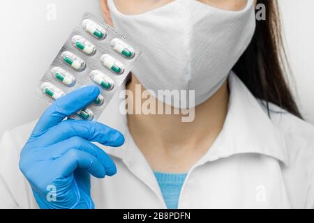 Coronavirus Prävention, die Vitamine zur Stärkung der Immunität nimmt. Arzt in Schutzmaske und blaue Handschuhe mit Pillen in den Händen. Stockfoto