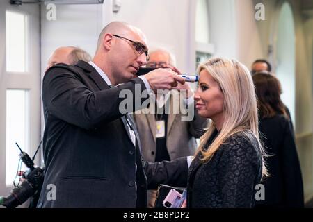 Washington, DC, USA. März 2020. Mitglieder der Medien werden auf Fieber untersucht, bevor US-Präsident Donald J. Trump am 22. März 2020 im Pressebriefingraum des Weißen Hauses in Washington, DC, USA, Bemerkungen zur Pandemie vorbringt. Bemühungen, die Coronavirus-COVID-19-Pandemie einzudämmen, haben zu Reiseunterbrechungen, Stornierungen von Sportveranstaltungen, Reinigungsarbeiten und Lebensmitteln und anderen Unannehmlichkeiten geführt.Credit: Jim LoScalzo/Pool über CNP   Usage Worldwide Credit: Dpa/Alamy Live News Stockfoto