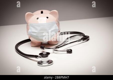 Stethoskop und Piggy Bank tragen medizinische Gesichtsmaske. Stockfoto