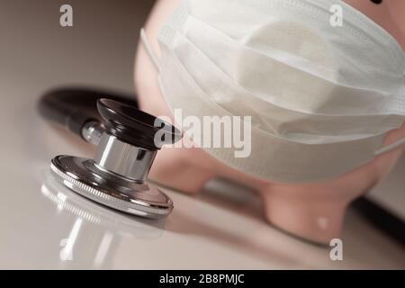 Stethoskop und Piggy Bank tragen medizinische Gesichtsmaske. Stockfoto