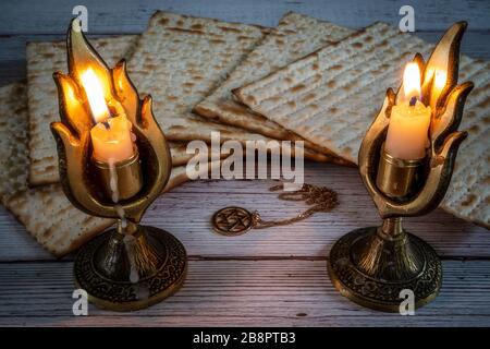 Passahmatzos, zwei Kerzenleuchter mit brennenden Kerzen und David Halskette auf Holzhintergrund Stockfoto