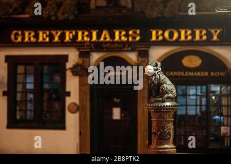 Edinburgh, Schottland, Großbritannien. März 2020. Eine Statue von Greyfriars Bobby trägt eine Gesichtsmaske inmitten der Pandemie von Coronavirus, vor einem geschlossenen Pub, der seinen Namen trägt. Gutschrift: Andrew Perry/Alamy Stockfoto