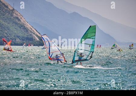 Riva del Garda, Lago di Garda, Italien - 12. Juni 2018: Windsurfer surfen auf Wellen im Gardasee, Fahrer surfen mit hoher Geschwindigkeit am Gardasee, R. Stockfoto