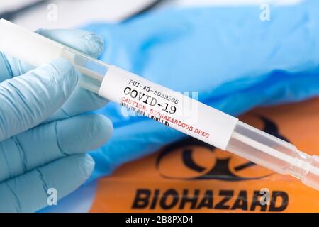 Coronavirus Covid-19 Atemspritzprobe Tupfer Reagenzglas mit Handschuhen, Maske und Beutel mit biologischer Gefährdung. Stockfoto