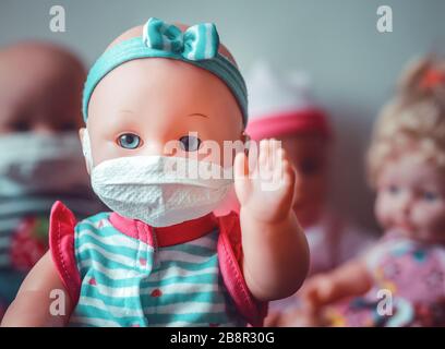 Eine Babypuppe, die Sicherheit beim tragen einer Maske darstellt, um Ansteckungen mit anderen Puppen zu vermeiden Stockfoto