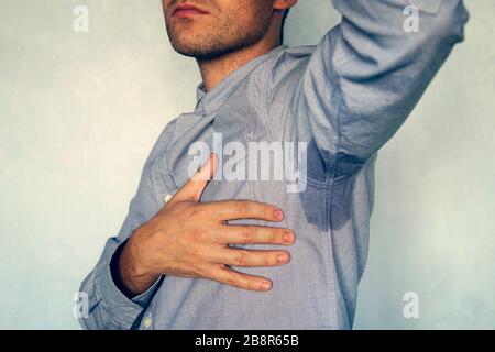 Junger Mann mit schwitzen unter der Achsel. Nasser Fleck auf meinem blauen Hemd aus dem Schweiß. Stockfoto