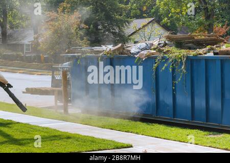 Rasengras in Rollen auf Paletten gegen die Straße der rollende Rasenplatz bereit für die Verlegung und beladene Müllcontainer in der Nähe des Baues städtisches Landschaftsdesign Stockfoto