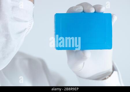 Seife für die persönliche Reinigung gegen Viren und Bakterien. Blaue Seife in einer Hand mit Handschuhen. Im Studio wurde ein Foto gemacht. Stockfoto