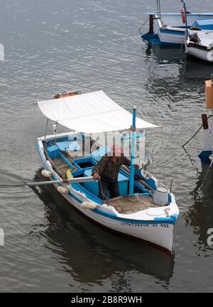 Fischer rudert sein Fischerboot in den griechischen Hafen von Kamini auf der Insel Hydra, Griechenland Stockfoto