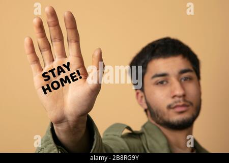 Der junge Mann erreicht seinen Arm und bittet, wegen der Koronakrise zu Hause zu bleiben Stockfoto