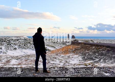 Ein männlicher Reisender, der die Landschaft mit Lóndrangar in der Ferne betrachtet Stockfoto