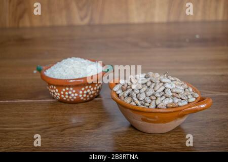 Tonbehälter im mexikanischen Stil mit Reiskörnern und Bohnen auf Holzbrettern Stockfoto