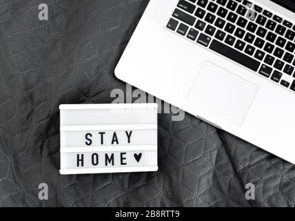 Leuchtkasten mit "Bleibe zu Hause"-Text auf Holzhintergrund. Flat-Lay-Covid-19-Angebot in Draufsicht Stockfoto