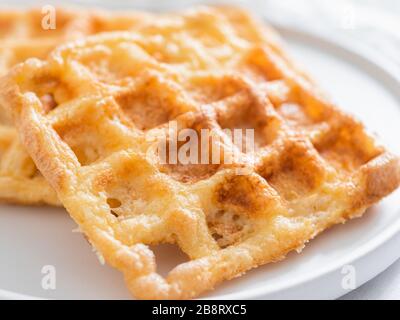 Perfekte herzhaften keto Waffeln. Zwei Zutaten chaffles auf die Platte über der weißen Marmor Hintergrund. Eier und Parmesan low carb Waffeln. Extreme Nahaufnahme. Stockfoto