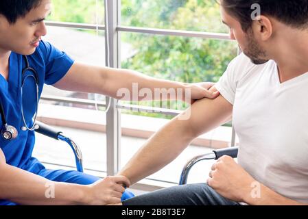 Asiatischer Arzt Therapeut massiert Arm des männlichen Athleten Patienten in der Klinik für körperliche Therapie Konzept Stockfoto