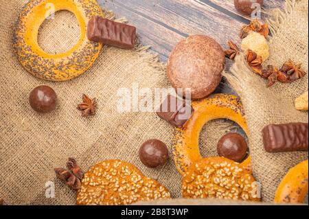 Bagels, Schokoladenkuchen, Plätzchen, Schokolade und ein Stück grober Homespun-Qualität auf Holzgrund. Nahaufnahme Stockfoto