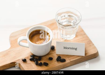 Frische Tasse Espresso-Kaffee zum Frühstück auf Holzplatte mit Grußkarte für den guten Morgen Stockfoto