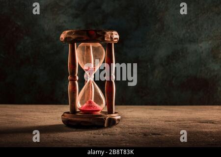 Das Konzept der Zeit läuft aus. Eine Sanduhr mit durchfallendem Sand, auf dunklem Hintergrund mit einem Ort für Text, gezungtes Bild Stockfoto