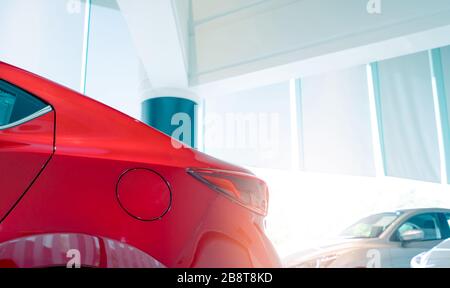 Schließen Sie die Tankklappe des roten Autos. Neues und glänzendes Luxusauto, das in einem modernen Ausstellungsraum zum Verkauf steht. Autohändleramt. Geschäftskonzept Elektroauto. Stockfoto