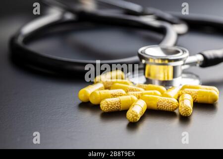 Vitaminkapseln. Vitamin-C-Pillen und Stethoskop auf schwarzem Hintergrund. Stockfoto