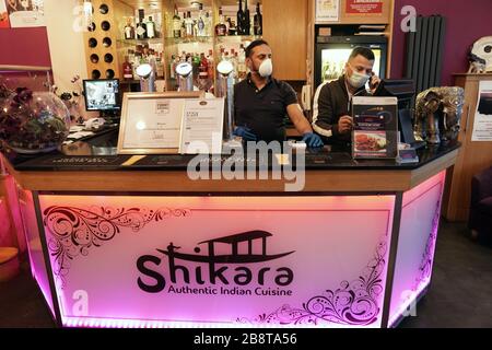 Die Mitarbeiter tragen Masken, wenn sie Bestellungen im Shikara Indian Restaurant in Whitley Bay, Tyne and Wear bearbeiten, wo sie das Restaurant geschlossen haben, um Kunden abzusetzen und im Rahmen der Reaktion Großbritanniens auf die Coronavirus Pandemie mit dem Mitnehmen von Mahlzeiten und Lieferungen zu beginnen. Stockfoto