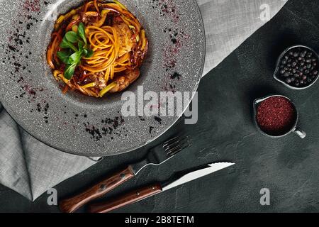 Spaghetti mit Ente und Gemüse. Italienische Küche, schöne Nudelgerichte auf grauem Teller und dunklem Hintergrund. Lebensmittelfoto, Werbebanner, V Stockfoto