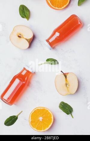 Flaschen mit gesunden Fruchtsäften, Äpfeln und Orangen auf weißem Tisch Stockfoto