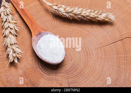 Ähren von Weizen und Mehl im Holzlöffel auf dem Tisch Stockfoto