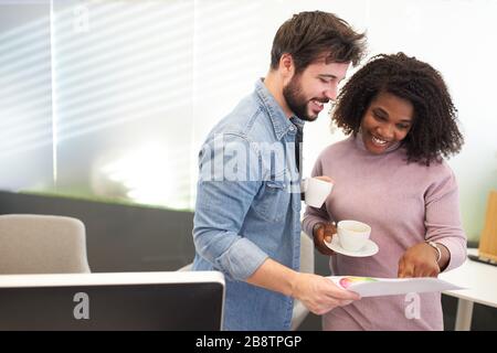 Junge Geschäftsleute und afrikanische Kollegen sehen sich ein Dokument an Stockfoto