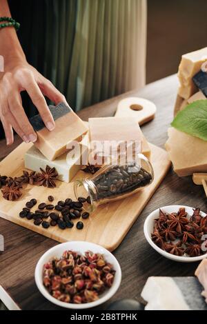 Frau, die Seifenleiste mit Kaffeebohnen und Anisblüten auf dem Schneidebrett aufsetzt, um ein schönes Foto für ihren Blog zu machen Stockfoto