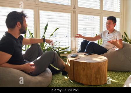 Zwei junge Geschäftsleute unterhalten kleine Gespräche in der Lounge oder im Chill-out-Bereich im Büro Stockfoto