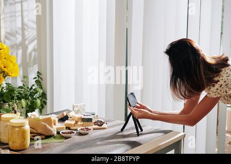 Frau setzt Smartphone auf Stativ und fotografiert handgemachte Seife für ihren Blog oder Online-Shop Stockfoto