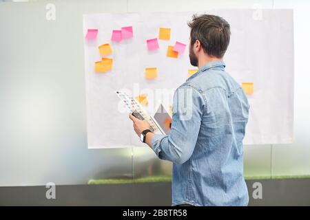 Business man im Brainstorming-Workshop, der Ideen auf Haftnotizen bewertet Stockfoto