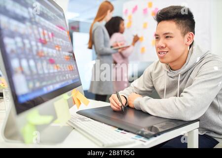 Asian als Grafikdesigner mit Stift und Tablett gestaltet das Layout für eine Website Stockfoto