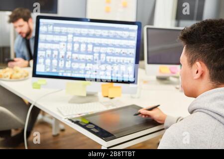 Junger Mann als Grafikdesigner auf einem Tablet-Computer, der eine Website entwirft Stockfoto