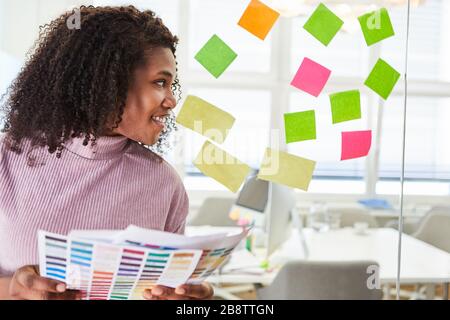 Afrikanerin als Grafikdesignerin, die kreatives Brainstorming mit bunten Haftnotizen macht Stockfoto