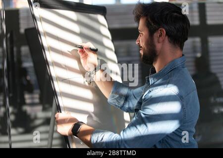 Der kreative Grafikdesigner oder Webentwickler auf dem Flipchart zeichnet eine Grafik Stockfoto