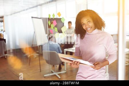 Afrikanerin lächelt vor Startteam im Büro Stockfoto