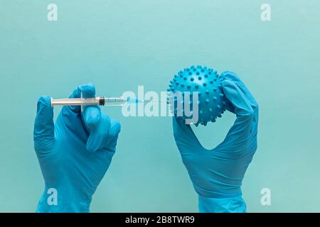 Hand in medizinischen Handschuh hält Spritze und abstrakte Virus-Modell Stockfoto